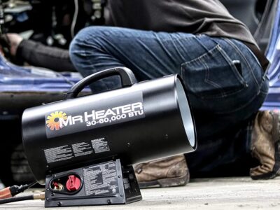 A man using an air heater to warm up a car