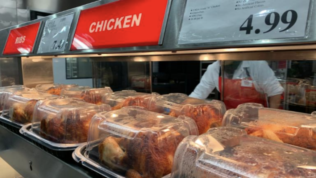 man stands before a chicken display, showcasing accessible and affordable poultry options