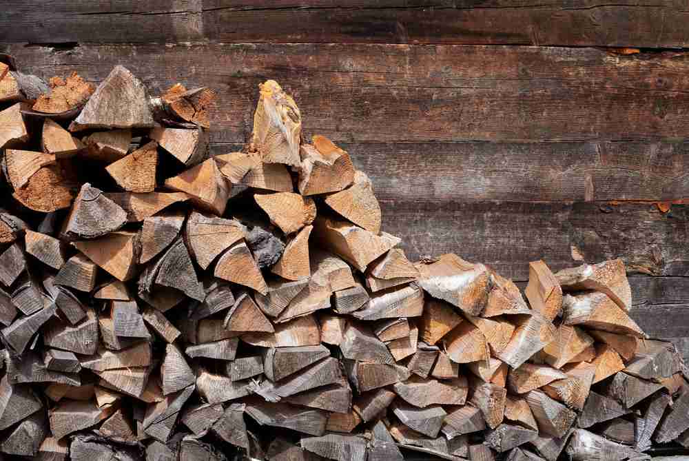 A pile of wood stacked against a wooden wall