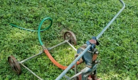 A lawn mower with a hose attached, designed for Traveling Sprinklers