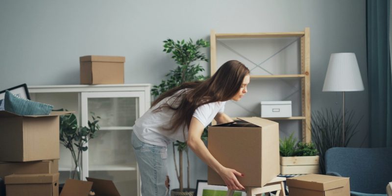 a woman moving boxes in a living room
